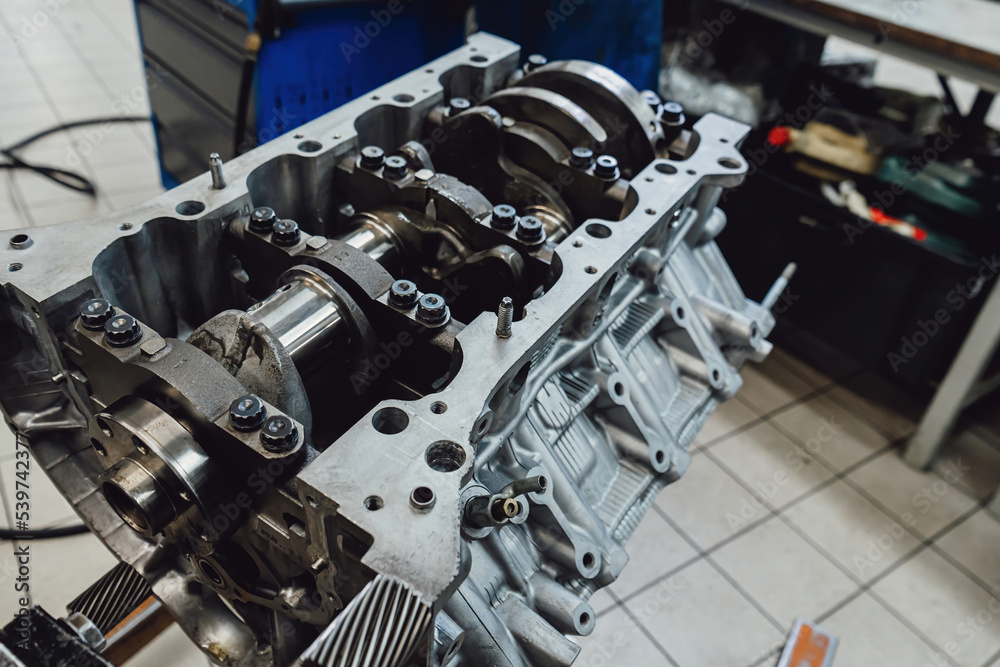 Car engine repair in a special technical engineering workshop. Concept of modern vehicle motor with metal, chrome, plastic parts, heavy industry, monochrome. Car engine repair in a special technical engineering workshop. Concept of modern vehicle motor with metal, chrome, plastic parts, heavy industry, monochrome.