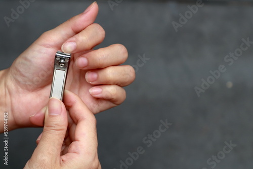 Hand holding nail clippers and cutting forefinger nail.