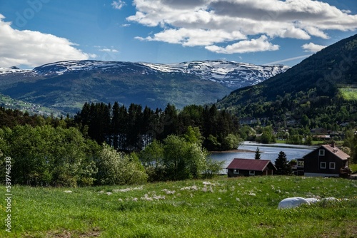 Beautiful view of wooden country houses by a river and forested mountains in Voss, Vestland, Norway photo