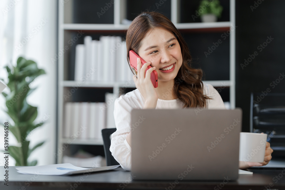 Pretty freelance asian business woman using mobile phone at working table in modern office. Pretty freelance asian business woman using mobile phone at working table in modern office.