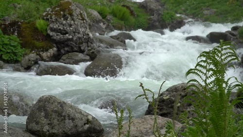 River close up. Stream clear flowing water. Shot of babbling splashing river with stone boulders