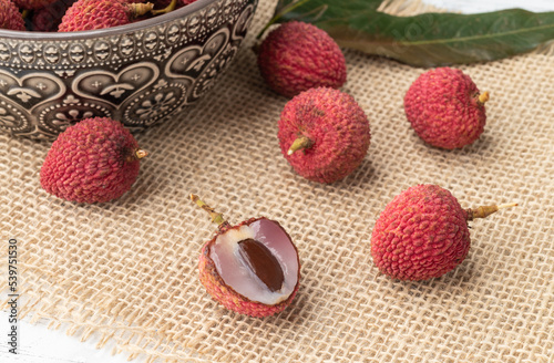 Lychees in a bowl with cut fruit over wooden table