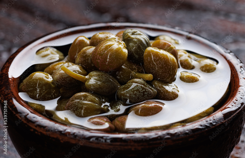Pickled capers in brine. Clay cup full of capers. Pickled capers in brine. Clay cup full of capers.