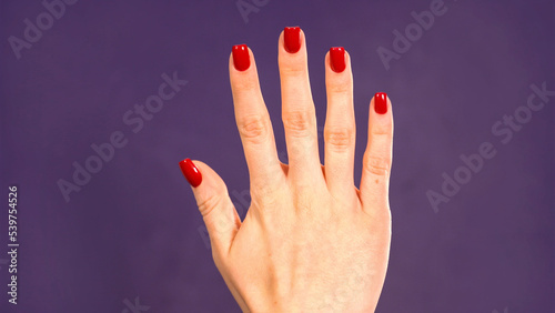 Female hand counting from 5 on purple background. Girl shows five fingers. Count