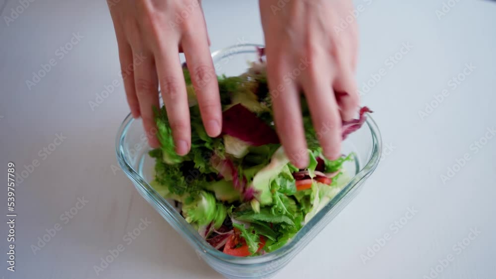 Women's hands in the foreground mixing with vegetable ingredients in fresh delicious salad, unrecognizable vegetarian, mother, preparing a dish with green leaves. Women's hands in the foreground mixing with vegetable ingredients in fresh delicious salad, unrecognizable vegetarian, mother, preparing a dish with green leaves.