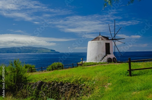 Beautiful scenery of an old windmill in green field by the sea in Corvo Island