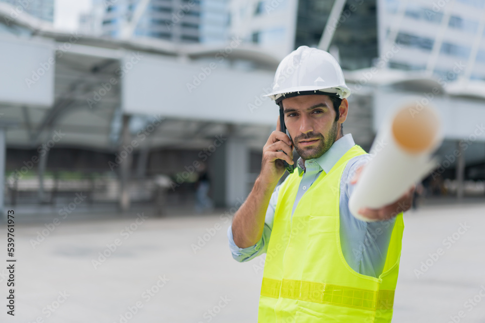 Man engineer standing on construction site. construction manager using walkie talkie. Engineer working on outdoor project and talking on phone Man engineer standing on construction site. construction manager using walkie talkie. Engineer working on outdoor project and talking on phone