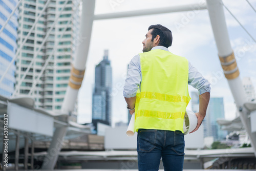 Man engineer standing on construction site. Engineer working on outdoor project and raising hands