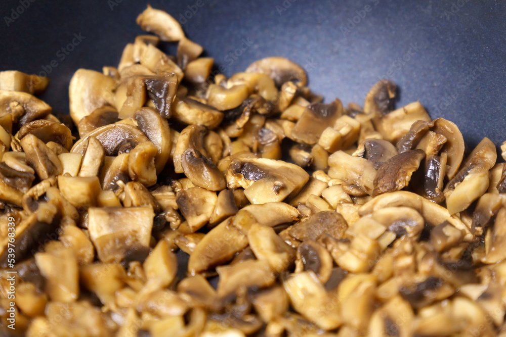 Cooking fried mushrooms, champignons in a pan. Close-up. Selective focus Cooking fried mushrooms, champignons in a pan. Close-up. Selective focus