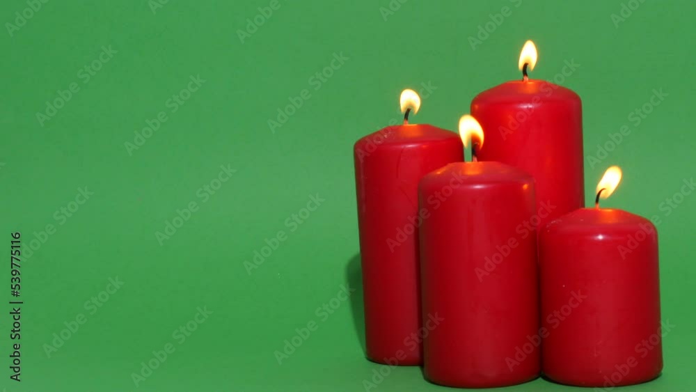 Thick red Christmas candles on a green chroma key background. The candle flame burns and dances
