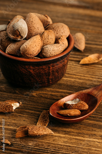 unpeeled almonds in a shell in a bowl, on a wooden table