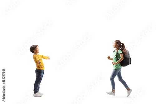 Full length profile shot of a schoolgirl running towards a little boy with arms wide spread