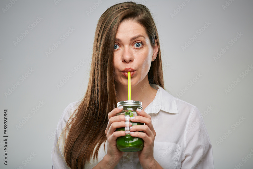 Young woman drinking green smoothie from glass jar. Isolated advertising female portrait. Young woman drinking green smoothie from glass jar. Isolated advertising female portrait.