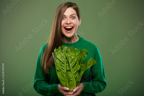 Happy laughing woman holding romaine lettuce salad. Advertising female portrait on green.