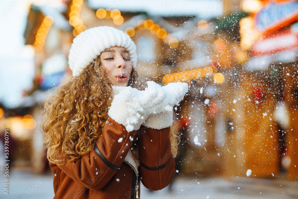 Close up Hands in warm mittens make snow in winter. Happy young woman in snowy winter park. Cold weather. Holidays, rest, travel concept.