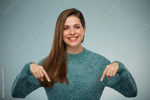 Smiling woman in green sweater pointing fingers down at copy space. Advertising female studio portrait. photo