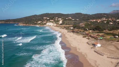 Pero beach of Cargese in Corsica on a sunny day. Drone aerial view of the Mediterranean Sea and sand beach with rocks at sunrise