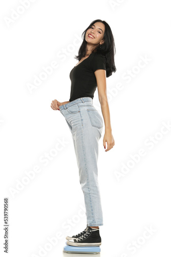 Weight loss happy woman standing on a scale, isolated on a white background. Slim Body