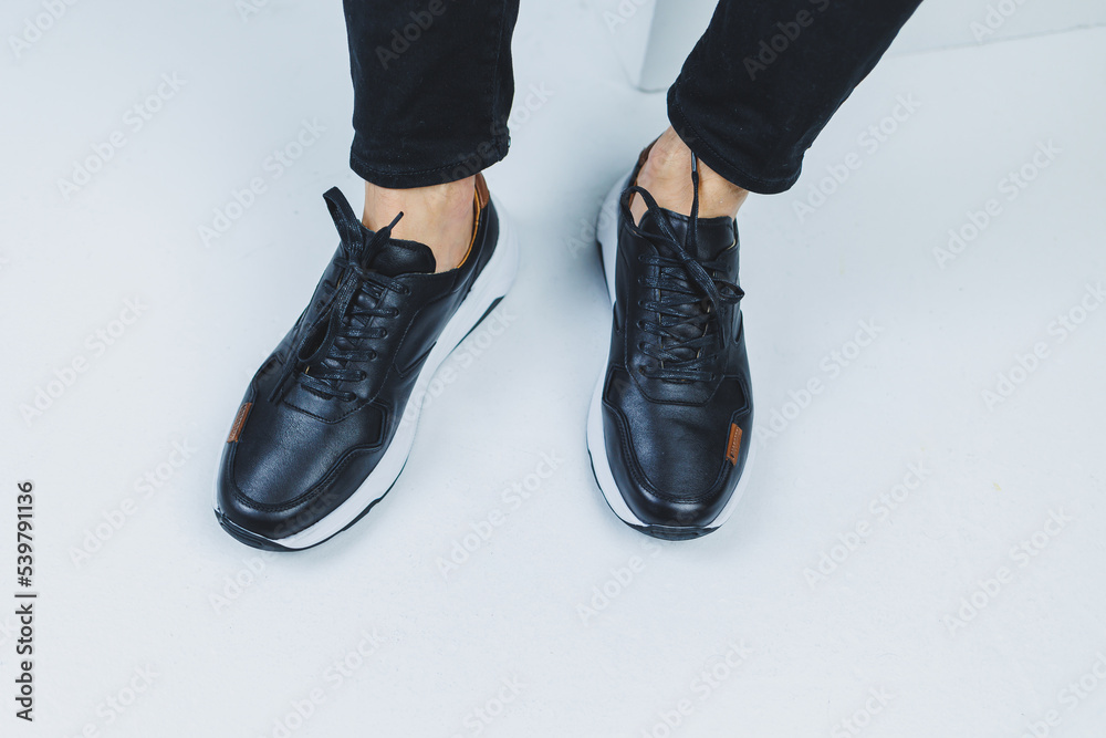 Men's legs in casual shoes of black color made of genuine leather, men on shoes in black sneakers. High quality photo Men's legs in casual shoes of black color made of genuine leather, men on shoes in black sneakers. High quality photo