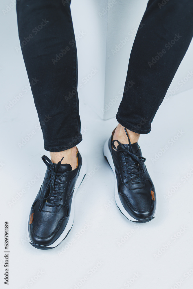 Men's legs in casual shoes of black color made of genuine leather, men on shoes in black sneakers. High quality photo