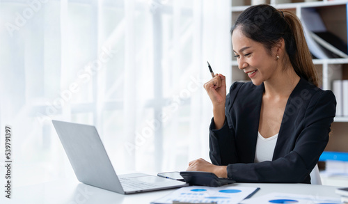 Attractive and confident, successful Asian businesswoman sitting on her laptop in the office.