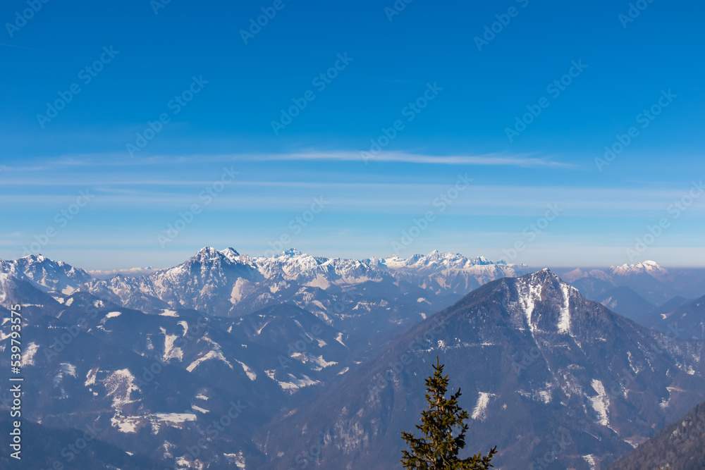Fototapeta premium Scenic view on snow capped mountain peaks of Karawanks in Carinthia (Kaernten), Austria. Julian Alps. Winter wonderland in Austrian Alps, Europe. View from Freiberg on Hochstuhl (Stol), Triglav, Kepa