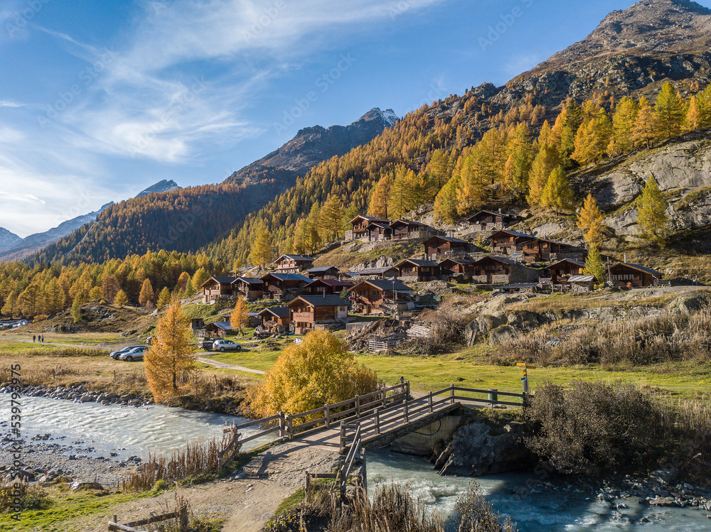 Blatten, Switzerland - October 19. 2022: Alps village with tradtional wooden chalets in autumn on the larch forest hillside in Loetschental valley, Canton Valais Blatten, Switzerland - October 19. 2022: Alps village with tradtional wooden chalets in autumn on the larch forest hillside in Loetschental valley, Canton Valais