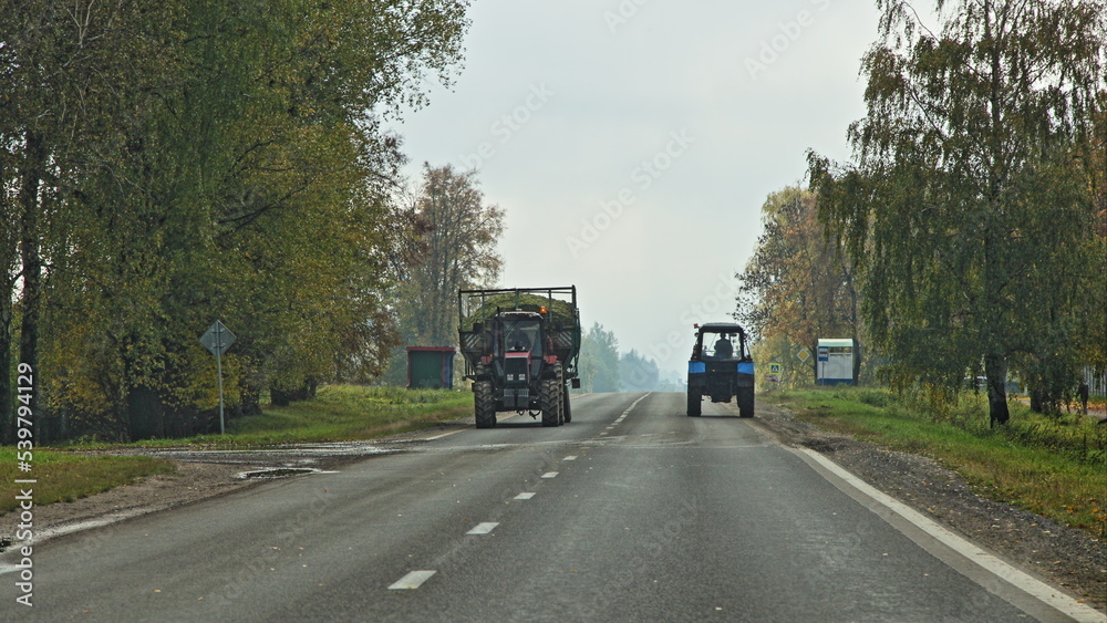 Obraz premium Tractors on village asphalted road in work . Rural transport