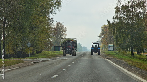 Tractors on village asphalted road in work . Rural transport