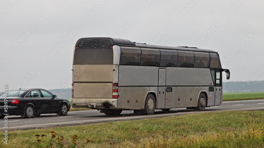 Car overtakes of old gray passenger bus a on motorway closeup . Passenger transportation safety
