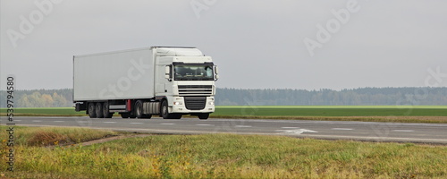 White semi truck move on countryside motorway road on green field . Front side view . Long hauls ransportation logistics