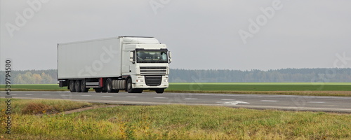 White semi truck move on countryside motorway road on green field . Front side view . Long hauls ransportation logistics photo