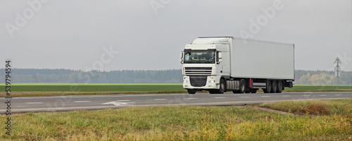 Obraz na płótnie White semi truck van drive on countryside highway road on green field . Front side view . International transportation logistics w salonie