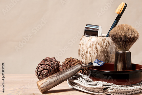 Beard trimmer and razor with brush and natural cream on bathroom table