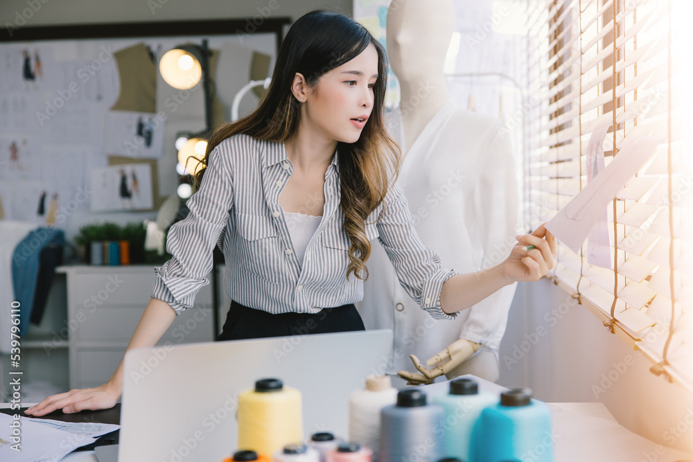 A beautiful seamstress with long hair writes in a notebook. the tailor creates a collection of outfits. young woman designer clothes notes ideas in notebook A beautiful seamstress with long hair writes in a notebook. the tailor creates a collection of outfits. young woman designer clothes notes ideas in notebook