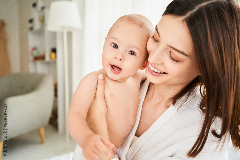 Portrait of caucasian newborn baby on bed with mother.