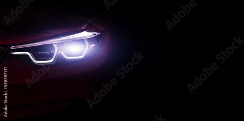 Car headlights close up , banner. Light of car headlights on a dark background, panorama, copy space.