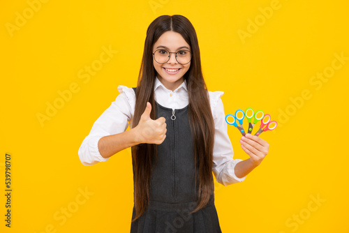 Teenage school girl with scissors  isolated on yellow background. Child creativity  arts and crafts.