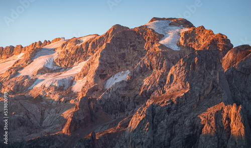 View of the Marmolada, the highest peak of the Dolomites, with its glaciers and the morning light, near the town of Canazei, Italy - August 2022. photo