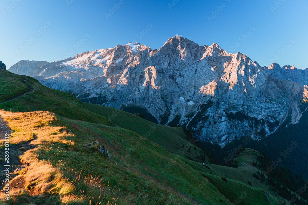 View of the Marmolada, the highest peak of the Dolomites, with its glaciers and the morning light, near the town of Canazei, Italy - August 2022.