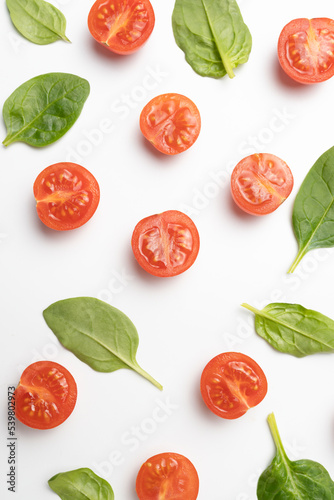 Beautiful border made of fresh cherry tomatoes with spinach leaves, Vegan diet food isolated on white, vegetable pattern, top view