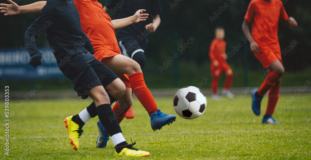 Competition between players running and kicking football ball. Young boys playing soccer game. Kids having fun in sport. Happy kids compete in football game. Running soccer players. Football school