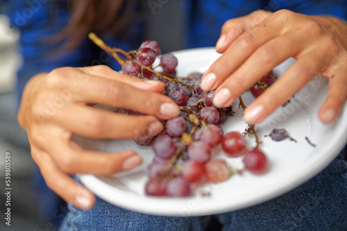 Closeup of a girl eating grapes from a plastic plate