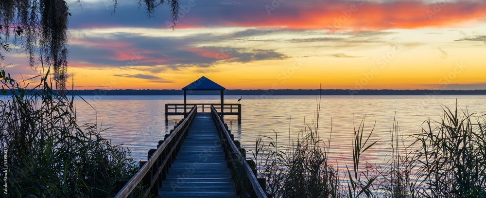 Wooden dock with railings to the Crescent Lake on the sunset - obrazy, fototapety, plakaty 