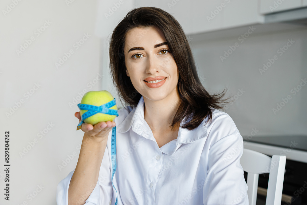 Body care. Cropped image of a nutritionist woman wrapped an apple a measuring tape showing that the result is great. Woman showed a good result from a balanced diet Body care. Cropped image of a nutritionist woman wrapped an apple a measuring tape showing that the result is great. Woman showed a good result from a balanced diet