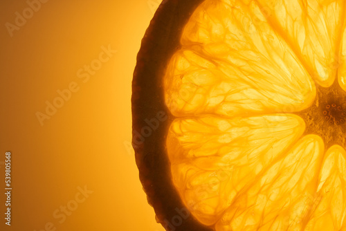 Slice of fresh juicy orange fruit close up on orange background. Macro photography concept.  photo