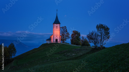 Jamnik church St Primus and Felician on the green hill at the dusk, Slovenia. Night alpine landscape, outdoor travel background