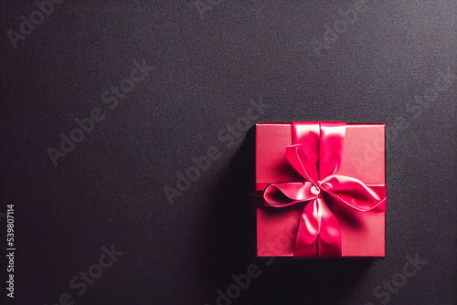 Top view of black Christmas boxes with red ribbon on a black background with copy space for text.