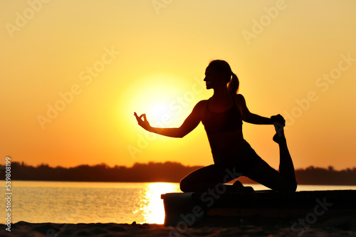 Silhouette of a  woman practicing pigeon yoga pose