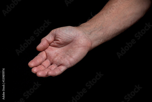 The outstretched hand of a caucasian man, isolated on black background. Black and white.